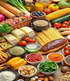 Overhead view of diverse fresh foods including vegetables, fruits, grains, pasta, cheese, and nuts on a wooden table