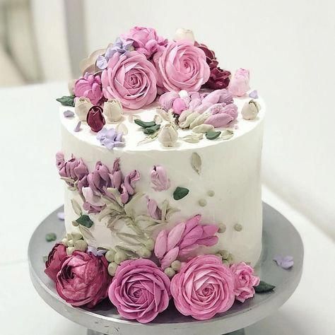 White cake topped and decorated with pink roses and pastel floral accents