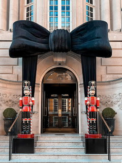 Building entrance with large black bow decoration and two life-size nutcracker soldier statues on either side