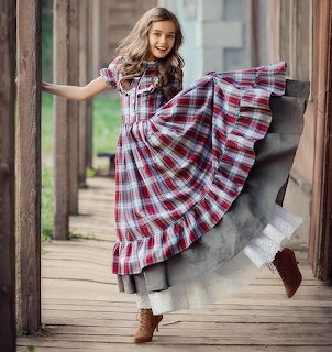 Woman in red plaid dress twirling on wooden porch with vintage columns