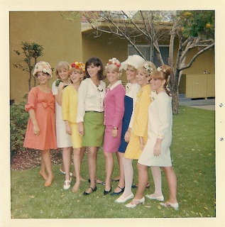 Group of women in pastel dresses posing outdoors on a grassy lawn