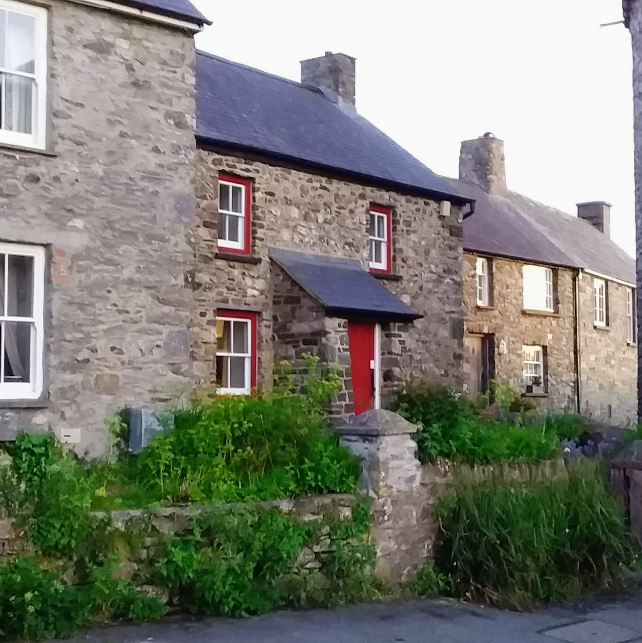 Stone cottages with slate roofs and a red front door beside a village lane