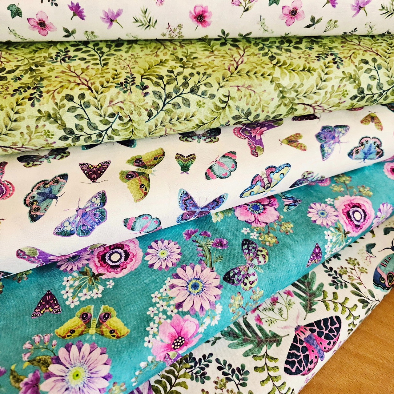Four layered fabric pieces with floral and butterfly patterns in pastel and bright colors