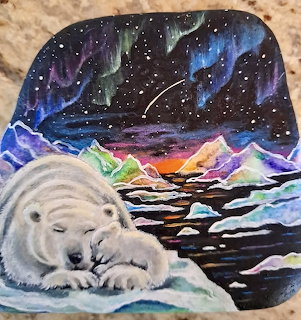 Polar bear sleeping on ice under northern lights with mountains and stars