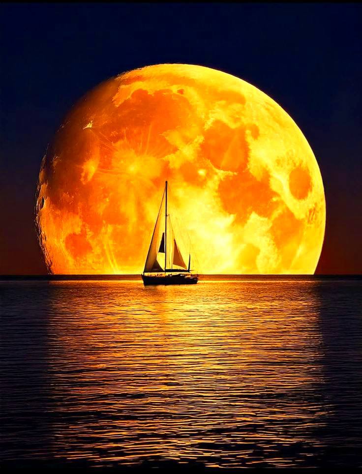 Sailboat silhouette on water in front of a giant orange moon at sunset