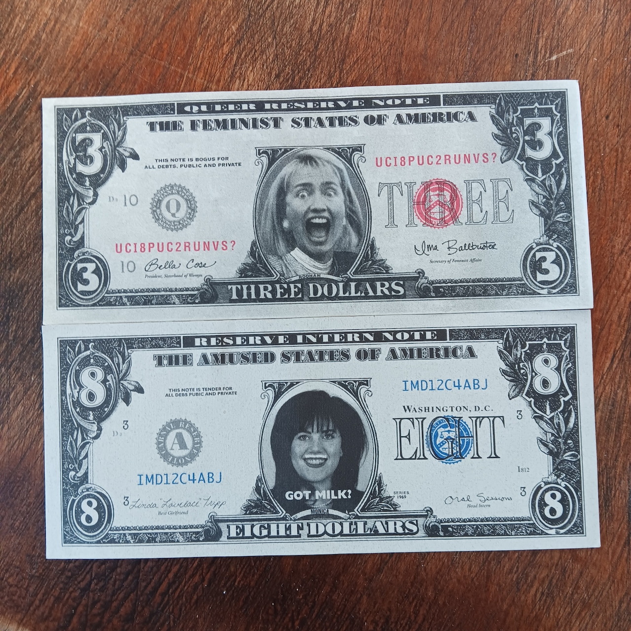 Two fake currency bills showing parody three and eight dollar denominations with modified portraits on wood background