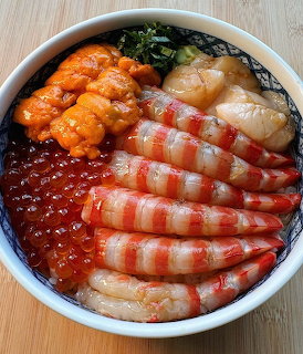 Japanese seafood donburi with shrimp sashimi, salmon roe, uni, and scallops in a patterned bowl