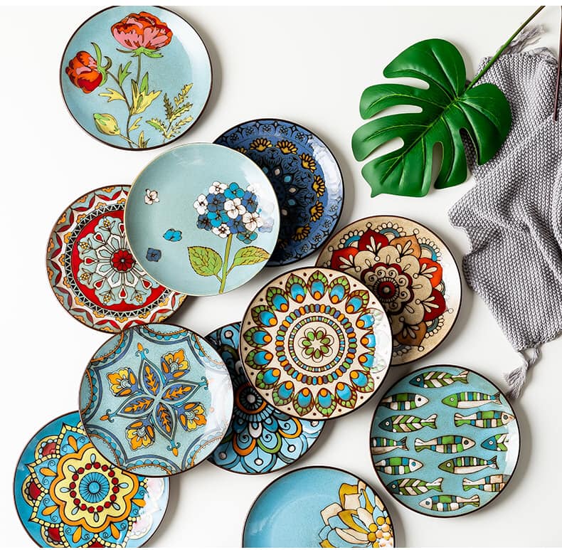 Overhead view of decorative ceramic plates with colorful floral and geometric patterns arranged on white surface