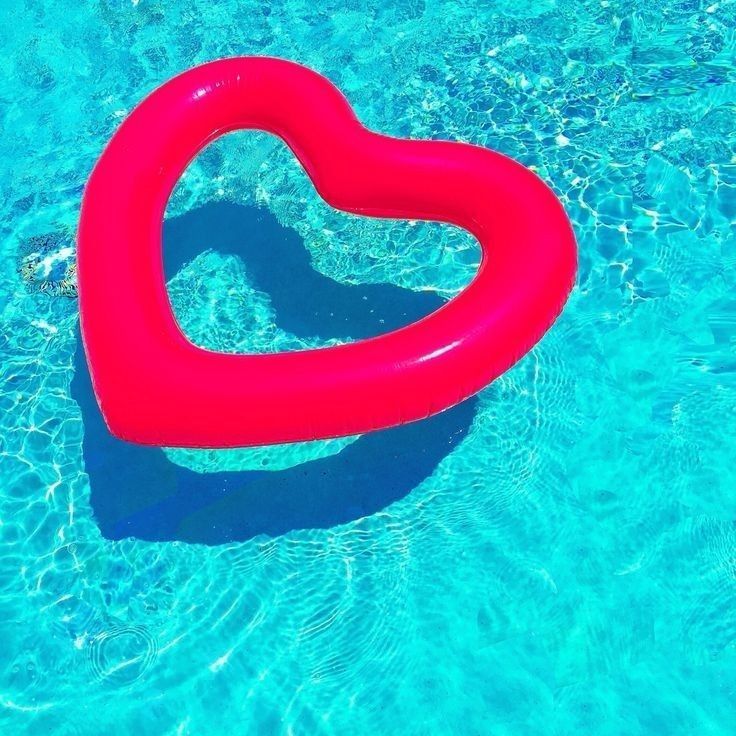 Red heart-shaped pool float on clear turquoise water