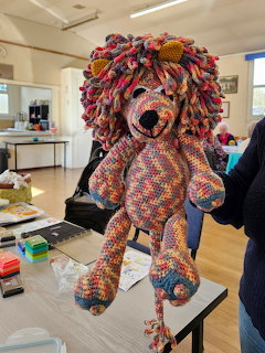 Handmade crochet lion toy with rainbow yarn mane and colorful granny square patchwork body