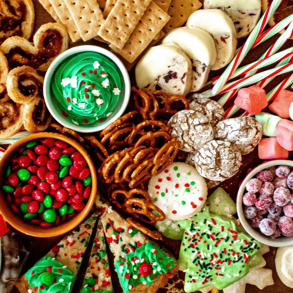 Overhead view of Christmas cookies, candy canes, pretzels, and festive treats arranged on wooden platter