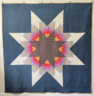 Geometric star quilt with colorful radiating points on blue background
