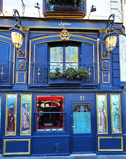 Ornate blue painted Parisian building facade with lanterns, Art Nouveau panels, and iron balcony
