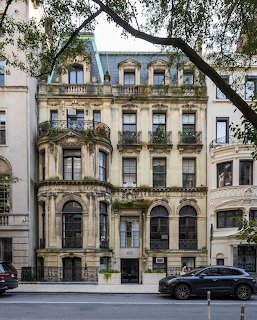 Elegant historic NYC mansion with ornate facade, balconies, and arched entrance on tree-lined street