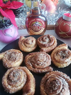 Plate of sugar-dusted cinnamon pastries with a syrup bottle behind it