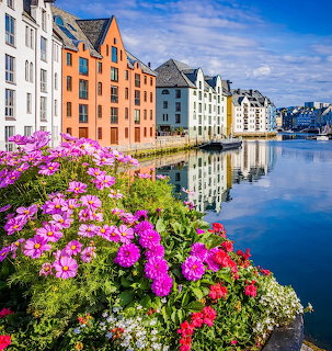 Colorful waterfront buildings in Ålesund Norway with pink flowers and water reflections