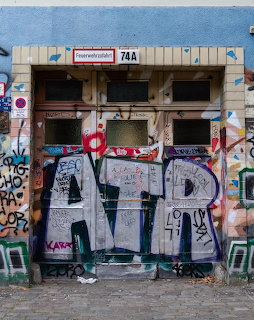 Graffiti-covered building entrance with tagged double doors and number 74A in Berlin