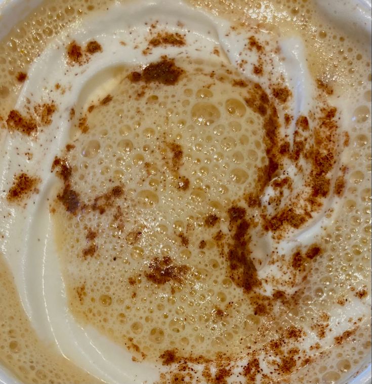 Top view of coffee with cinnamon-dusted foam in a white cup