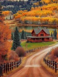 Red cottage by a lake with autumn trees and a winding dirt road