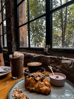 Croissant, coffee, and jam on a cafe table by a window