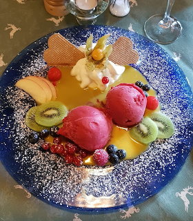 Colorful dessert platter with macarons, fruit, and white chocolate on blue speckled plate