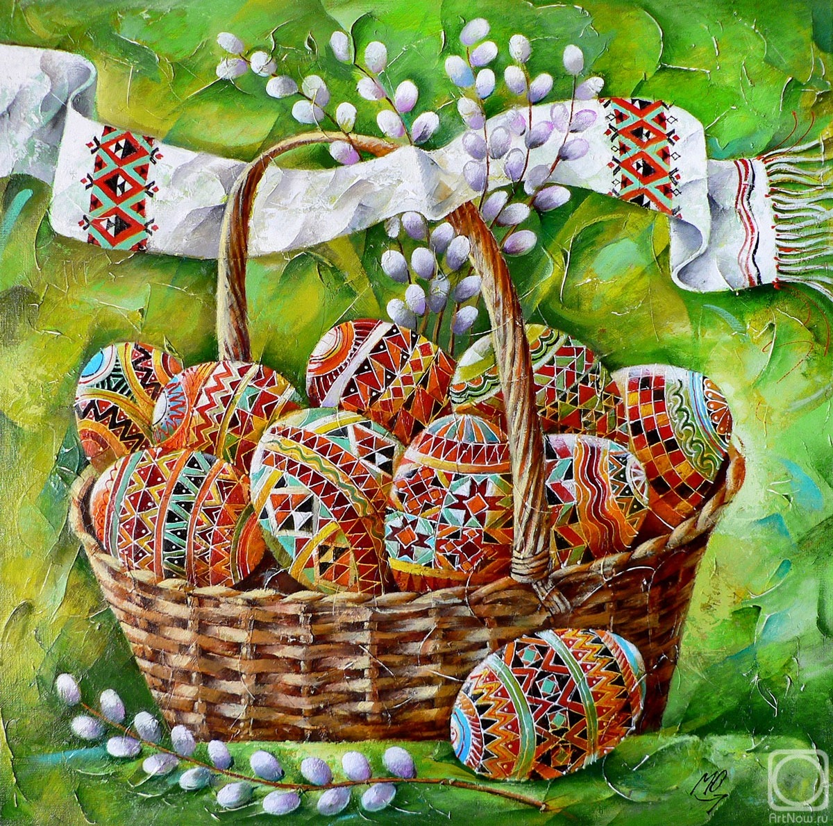 Wicker basket filled with ornately decorated Easter eggs surrounded by pussy willow branches on green fabric