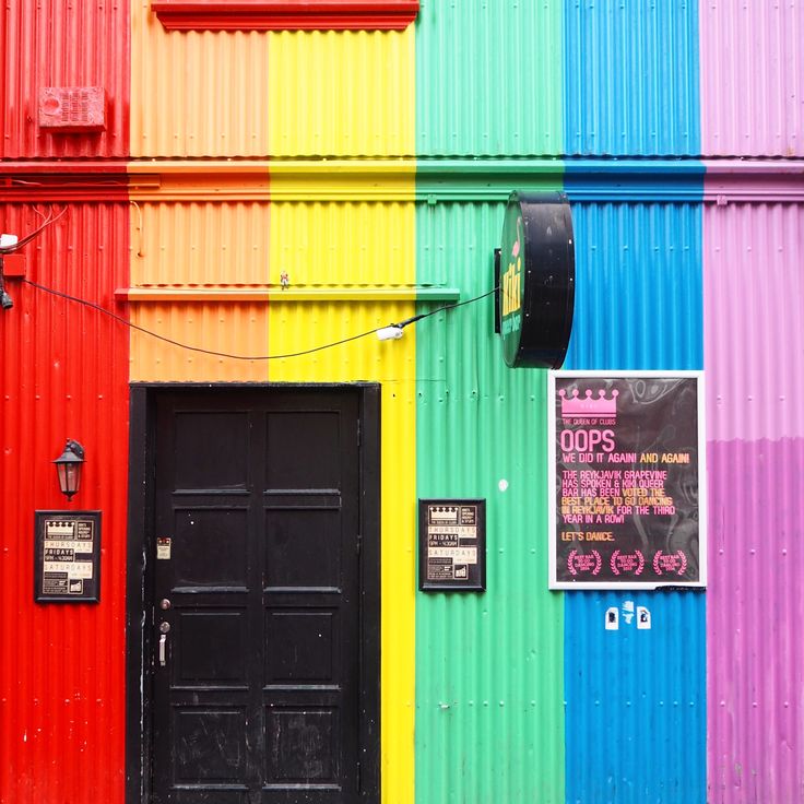 Colorful corrugated metal building wall with rainbow vertical stripes and black door