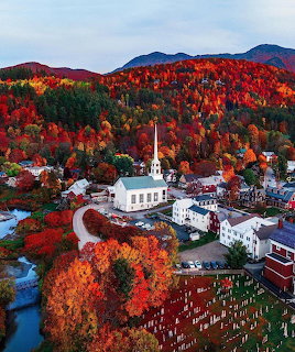 Aerial view of Stowe Vermont village with white church surrounded by colorful autumn foliage and mountains