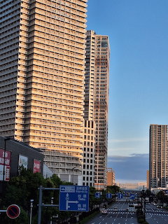 Tall apartment towers beside a city street with road signs and blue sky