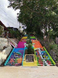 Bright multicolored outdoor staircase beneath large trees