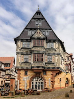 Historic German half-timbered building with pointed roof and ornate carvings in a town square