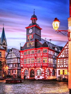 Historic red town hall with clock tower in European square at twilight