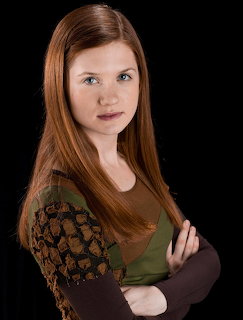 Studio portrait of Ginny Weasley with long red hair against a black background