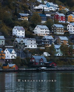 Colorful hillside houses along Hardangerfjord Norway with calm water reflections and autumn trees