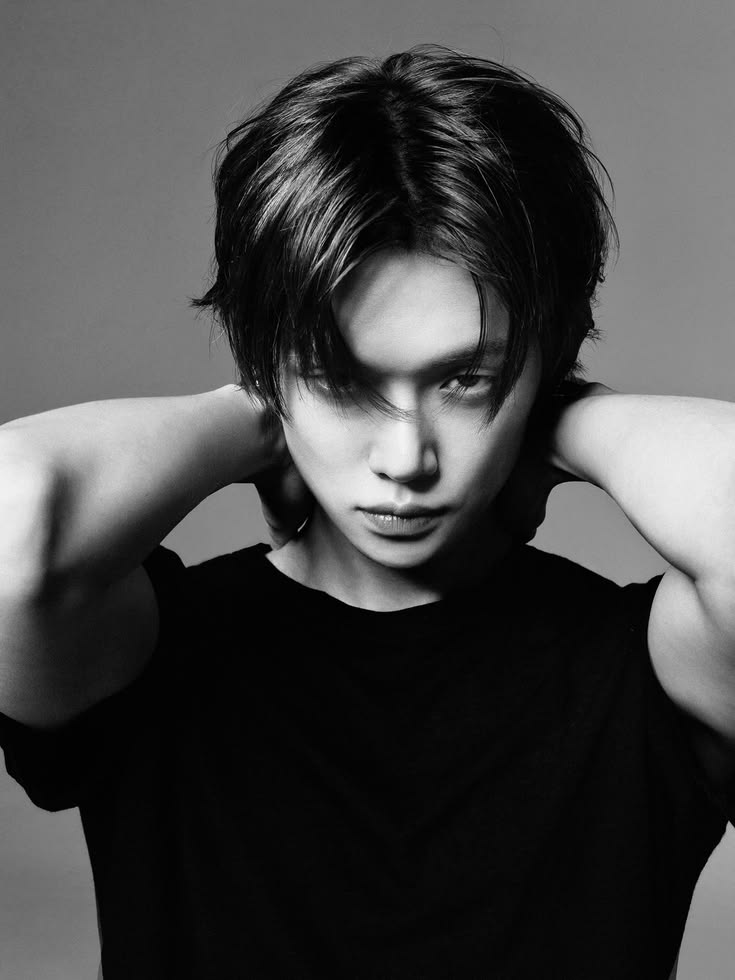 Black and white portrait of young man with dark hair looking at camera wearing black sleeveless top
