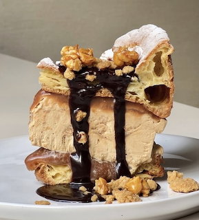 Slice of peanut butter layer cake with chocolate sauce, whipped cream, and peanut butter cookie pieces