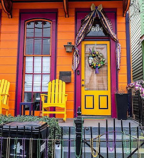 Bright orange house with purple door, yellow chairs, and colorful festive porch decorations