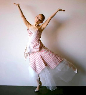 Woman in pink ballet dress with arms raised gracefully, wearing pointe shoes in dance pose