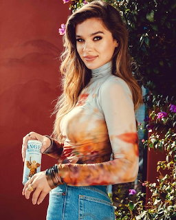 Young woman with ombre hair in casual top and jeans, holding drink can, smiling outdoors