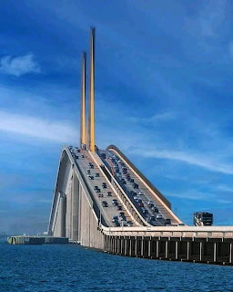 Sunshine Skyway Bridge over blue water with cars on the roadway beneath a cloudy sky