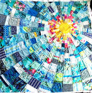 Circular starburst quilt pattern with blue and yellow patchwork fabrics radiating from center