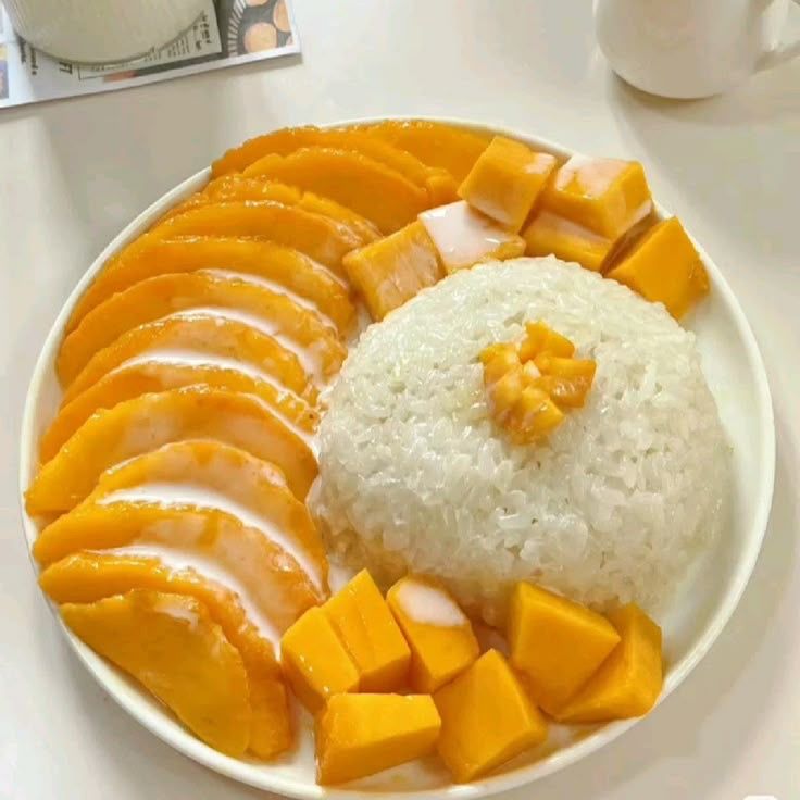 White sticky rice with fresh mango slices and cubes on a plate