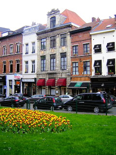Tulip flower bed in front of parked cars and historic buildings on a Brussels street