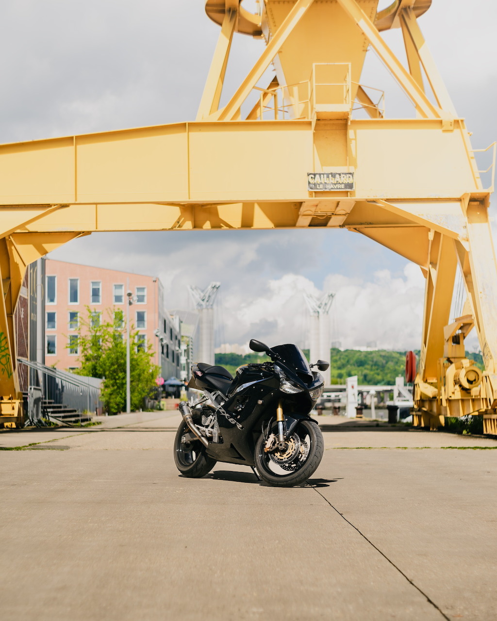 Black Kawasaki ZX-10R superbike parked under a yellow industrial crane on a concrete lot
