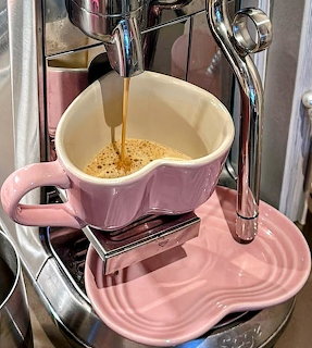 Espresso pouring into a pink heart-shaped mug beneath a coffee machine