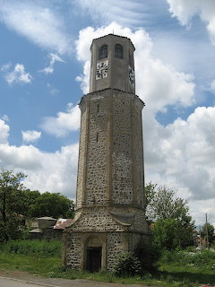 Stone clock tower in Karnobat, Bulgaria beneath a blue sky with clouds
