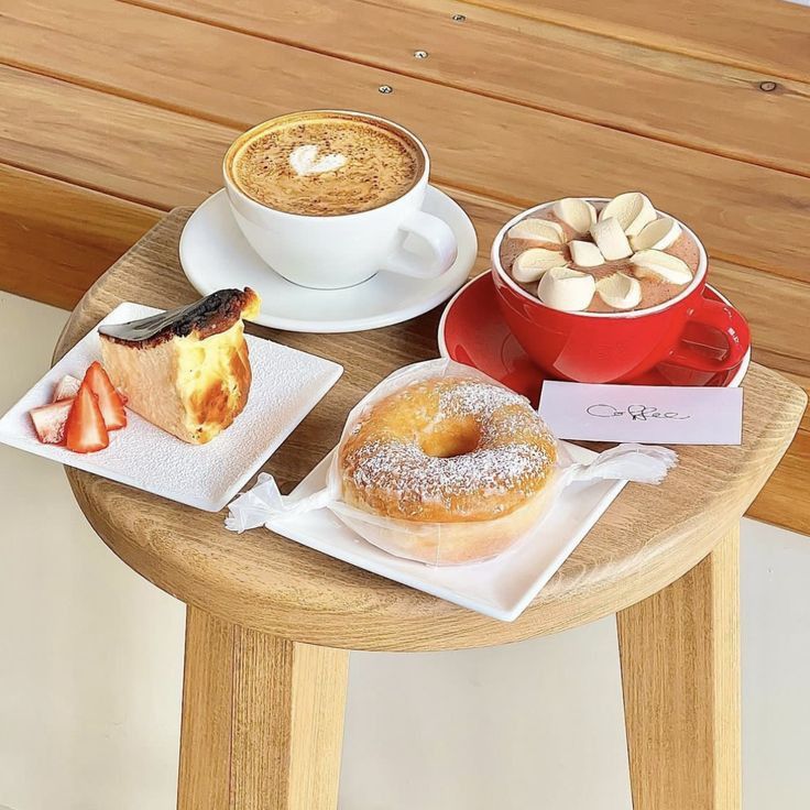 Coffee drinks with pastries and desserts arranged on a wooden table with white plates