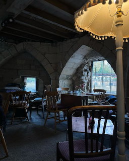 Dimly lit cafe interior with stone arches, wooden furniture, and decorative lampshades