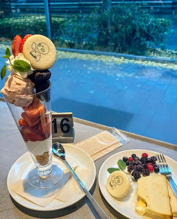 Layered dessert parfait and fruit plate on table beside blue swimming pool