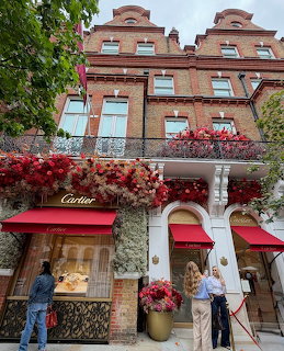 Red brick building in Chelsea London decorated with red flowers and floral arrangements on its facade